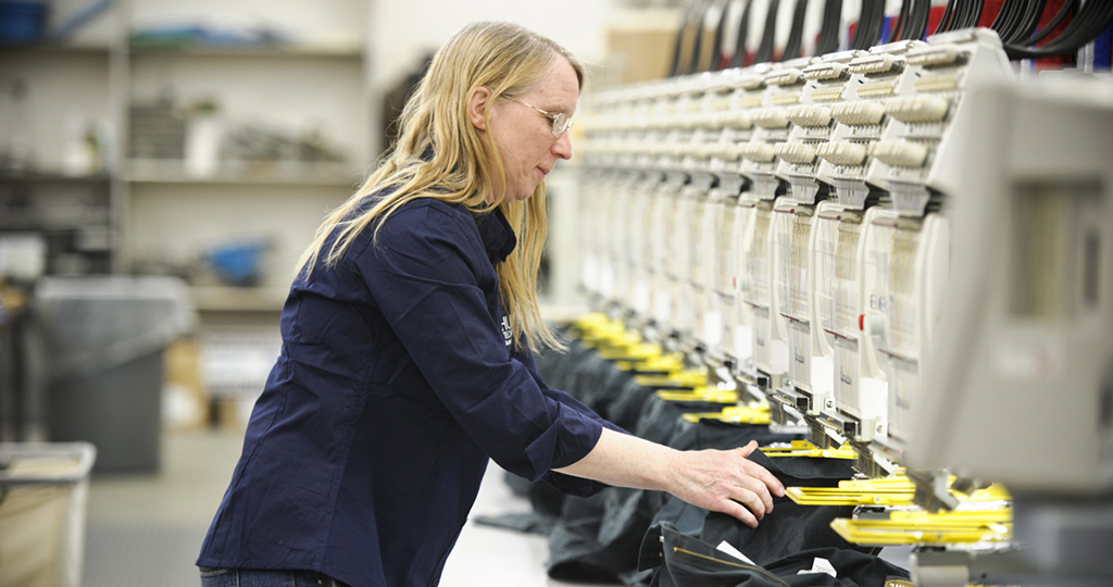 A woman loading shirts on an embroidery machine.